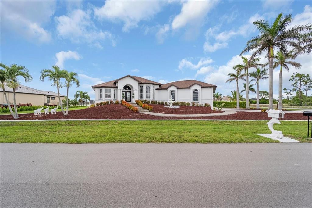 A single-story white house with a brown roof, palm trees, and a landscaped front yard — 4213 NW 28TH STREET, CAPE CORAL, FL
