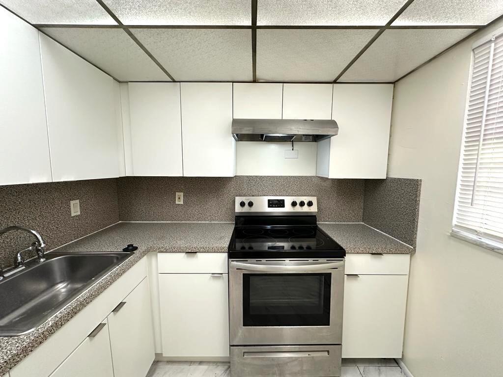 A kitchen features white cabinets, stainless steel appliances, and speckled laminate countertops — 15600 NW 7th Avenue # 516, Miami FL 33169, MIAMI, FL