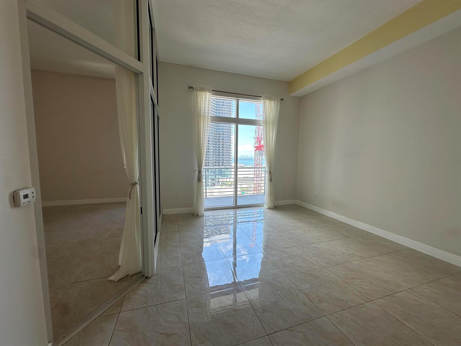 An empty room with light tile flooring, a glass balcony door, and a side partition — 234 NE 3rd Street, Miami FL 33132, MIAMI, FL