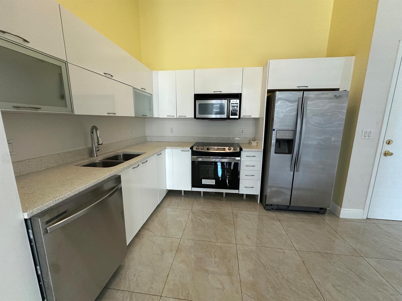 A kitchen features white flat-panel cabinets, stainless steel appliances, light countertops, and beige tile flooring — 234 NE 3rd Street, Miami FL 33132, MIAMI, FL