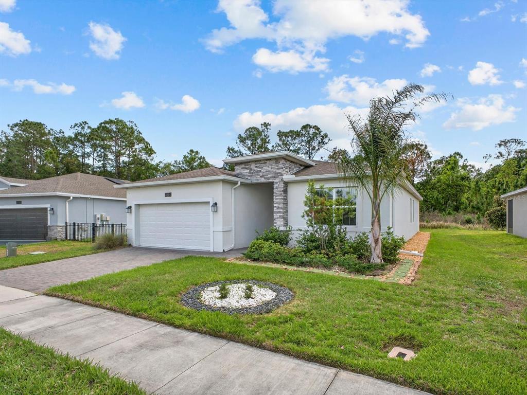 A single-story house with a white stucco facade, stone accents, and a paved driveway — 2894 CAMDEN WAY, DAVENPORT, FL