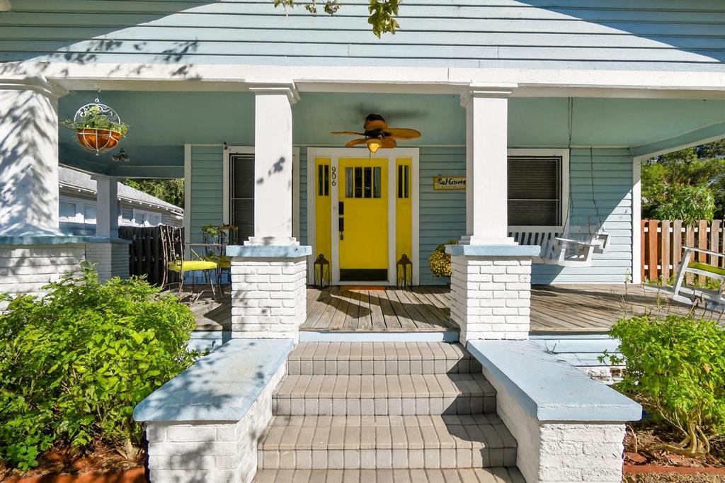 A light blue house features a bright yellow front door, a porch, and brick columns — 906 E HAMILTON AVENUE, TAMPA, FL