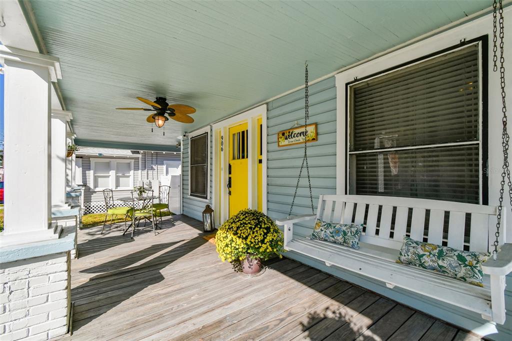 A covered front porch features a white swing, a yellow door, and a ceiling fan — 906 E HAMILTON AVENUE, TAMPA, FL