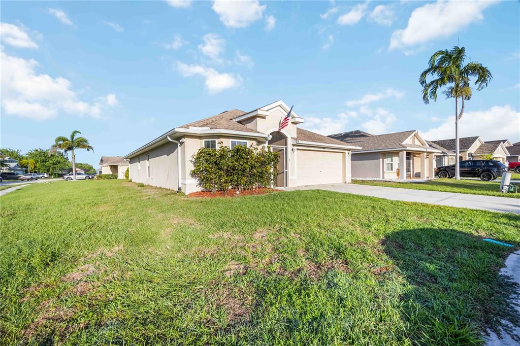 A single-story suburban house with a beige exterior, a two-car garage, and a front lawn — 9984 SPRING GULCH LANE, PUNTA GORDA, FL