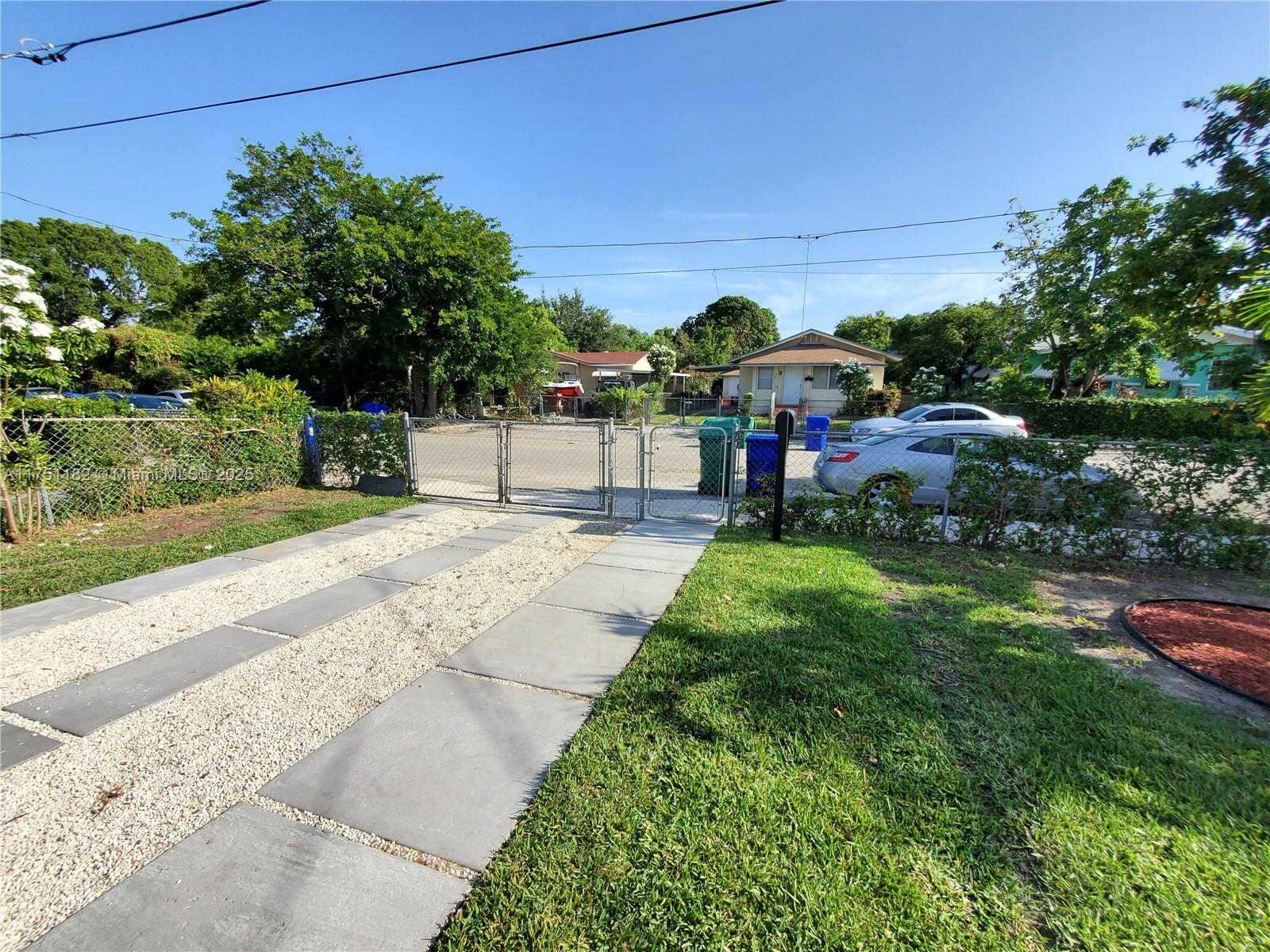 A gravel driveway with concrete pavers leads to a chain-link gate and fenced yard — 70 NW 33rd St, Miami FL 33127, MIAMI, FL