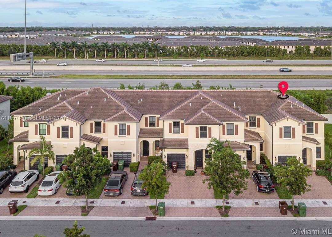 An aerial view shows a row of townhouses with driveways and a highway nearby — 10301 W 32nd Ln, Hialeah FL 33018, HIALEAH, FL