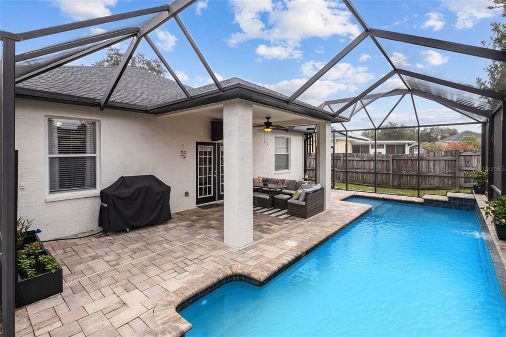 A covered patio with a pool, grill, and outdoor seating enclosed by a screen cage — 22633 MARSH WREN DRIVE, LAND O LAKES, FL
