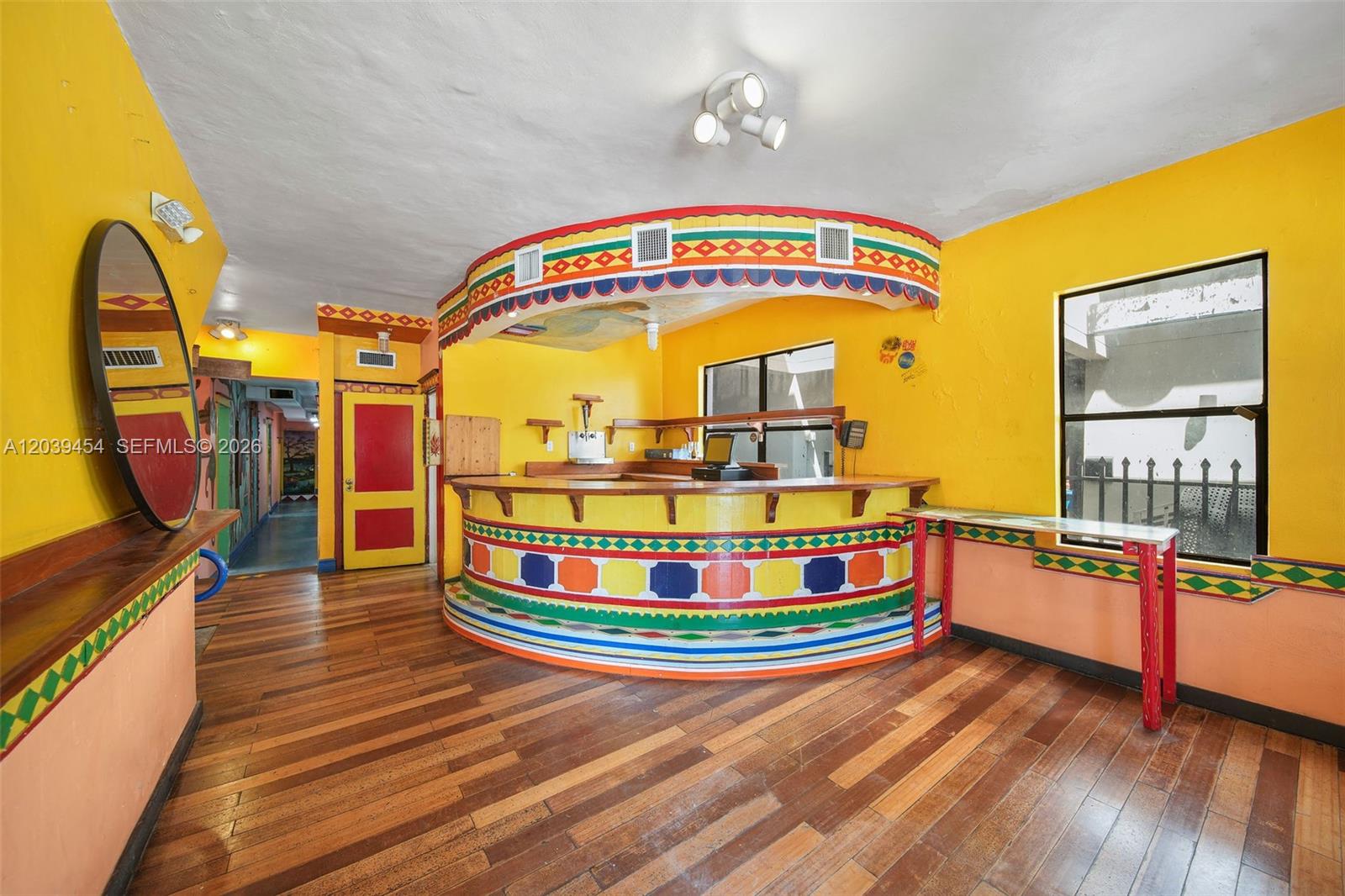 A brightly painted bar area features a curved counter, patterned trim, and hardwood flooring — 819 5th St, Miami Beach FL 33139, MIAMI BEACH, FL
