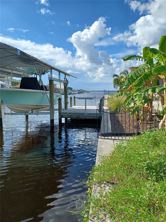 A boat on a lift sits beside a wooden dock along a canal with landscaping — 4195 SPIRE STREET, PORT CHARLOTTE, FL