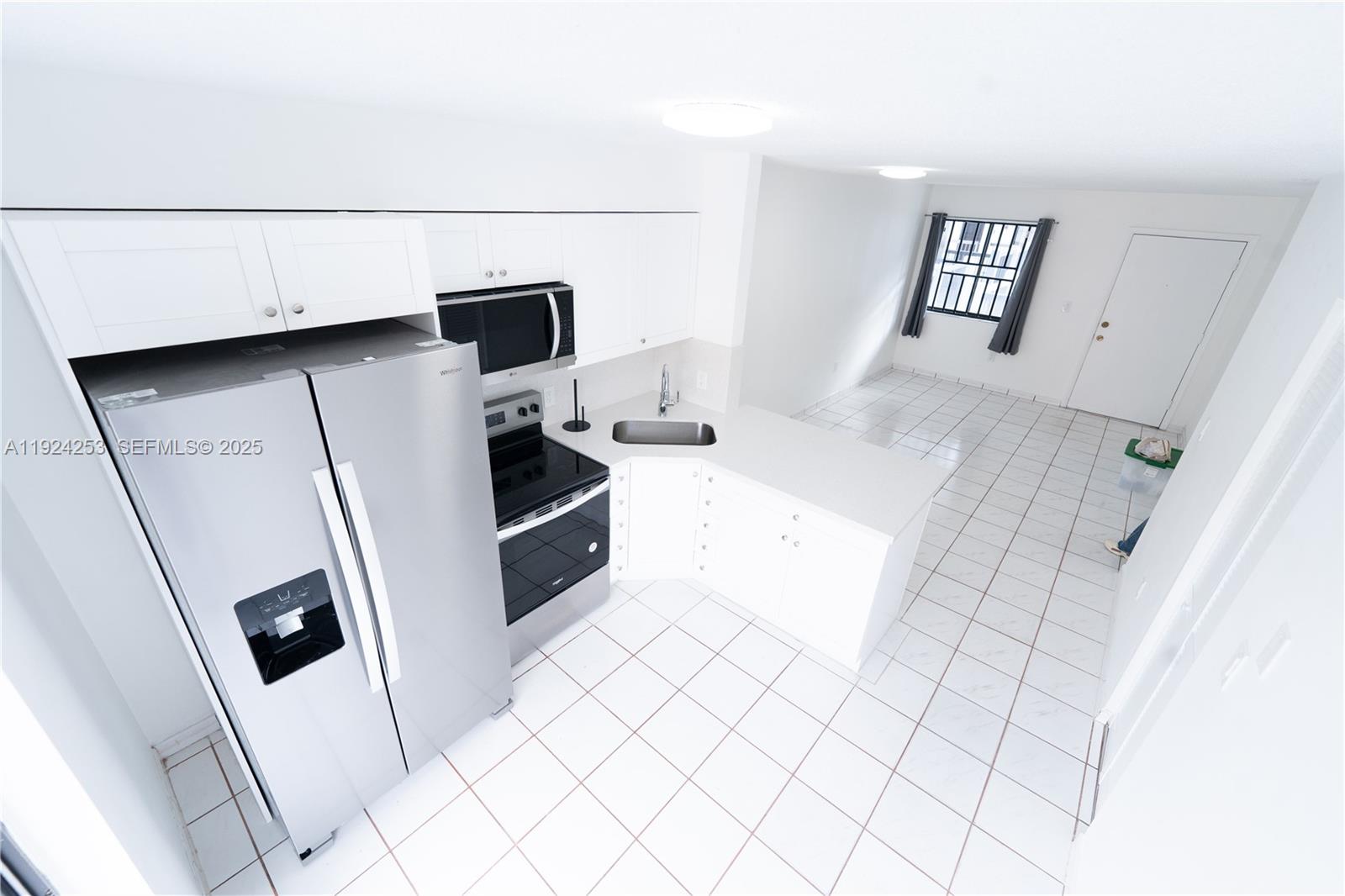 A high-angle view of a white kitchen with stainless steel appliances and tiled flooring — 5300 W 21st Ct # 311, Hialeah FL 33016, HIALEAH, FL