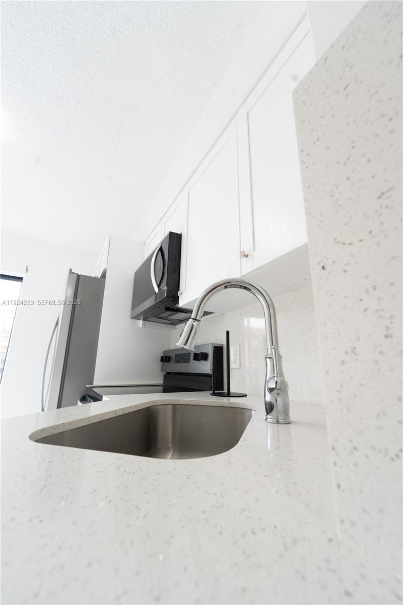 A kitchen features a stainless steel sink, white countertops, and white cabinetry — 5300 W 21st Ct # 311, Hialeah FL 33016, HIALEAH, FL