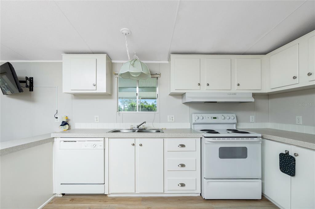 A kitchen features white cabinets, white appliances, a double sink, and light-colored countertops — 7364 TISA AVENUE, PORT CHARLOTTE, FL