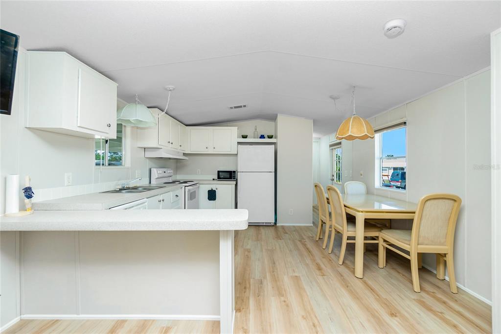 A kitchen and dining area with white cabinets, light wood-look flooring, and a dining set — 7364 TISA AVENUE, PORT CHARLOTTE, FL