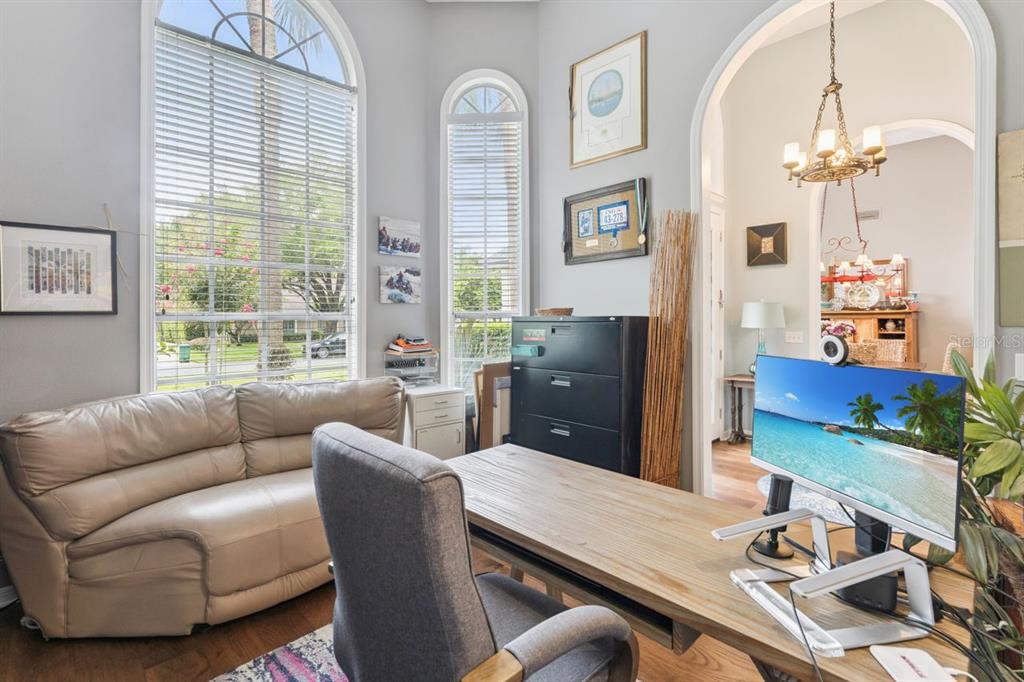A home office features a wooden desk, a leather sofa, and large arched windows — 1647 EAGLE NEST CIRCLE, WINTER SPRINGS, FL