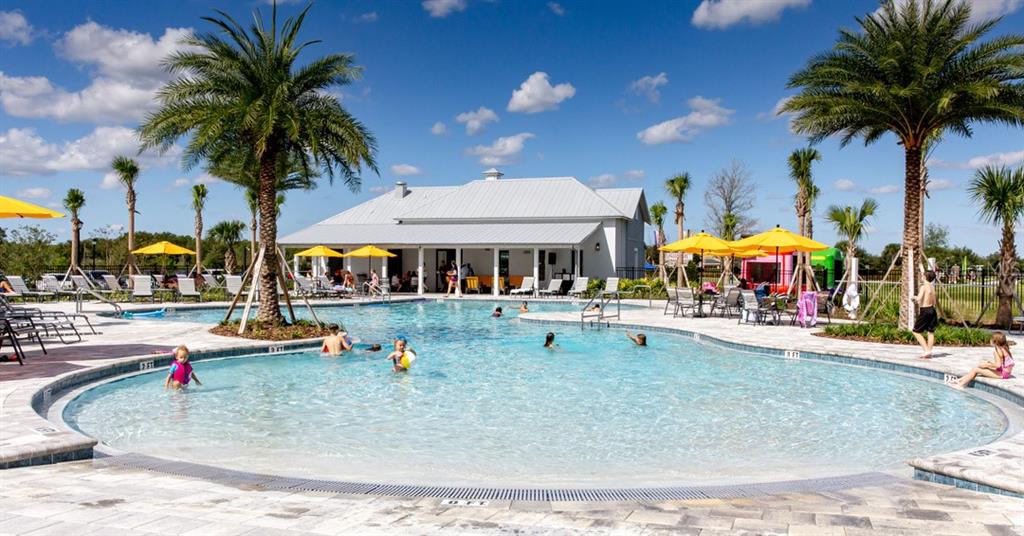 A swimming pool with a beach entry sits in front of a community clubhouse — 33220 CONTENTMENT WAY, WESLEY CHAPEL, FL