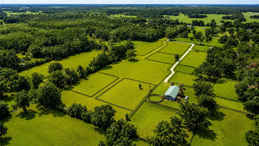 An aerial view shows a rural property with fenced pastures, a barn, and surrounding trees — TBD NW 100TH AVENUE, OCALA, FL