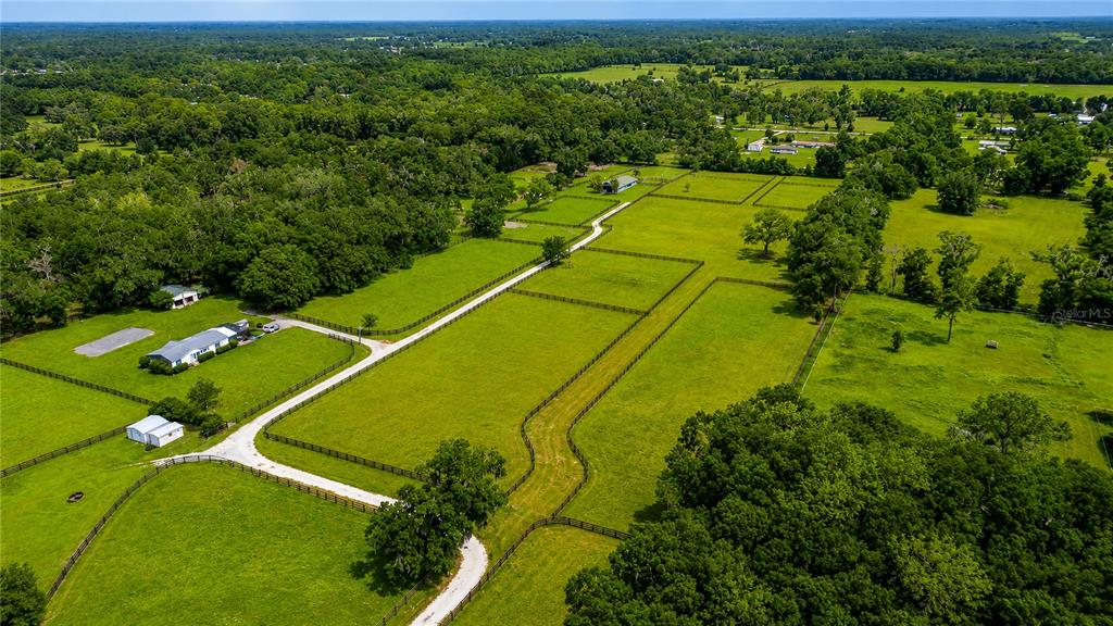 An aerial view shows a rural property with a house, outbuildings, and fenced pastures — TBD NW 100TH AVENUE, OCALA, FL