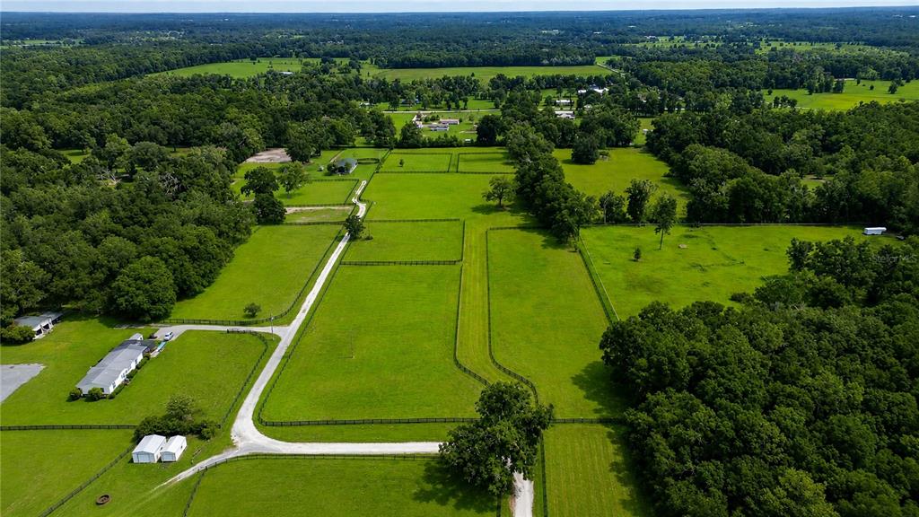 An aerial view shows a rural property with fenced pastures, a house, and surrounding woods — TBD NW 100TH AVENUE, OCALA, FL
