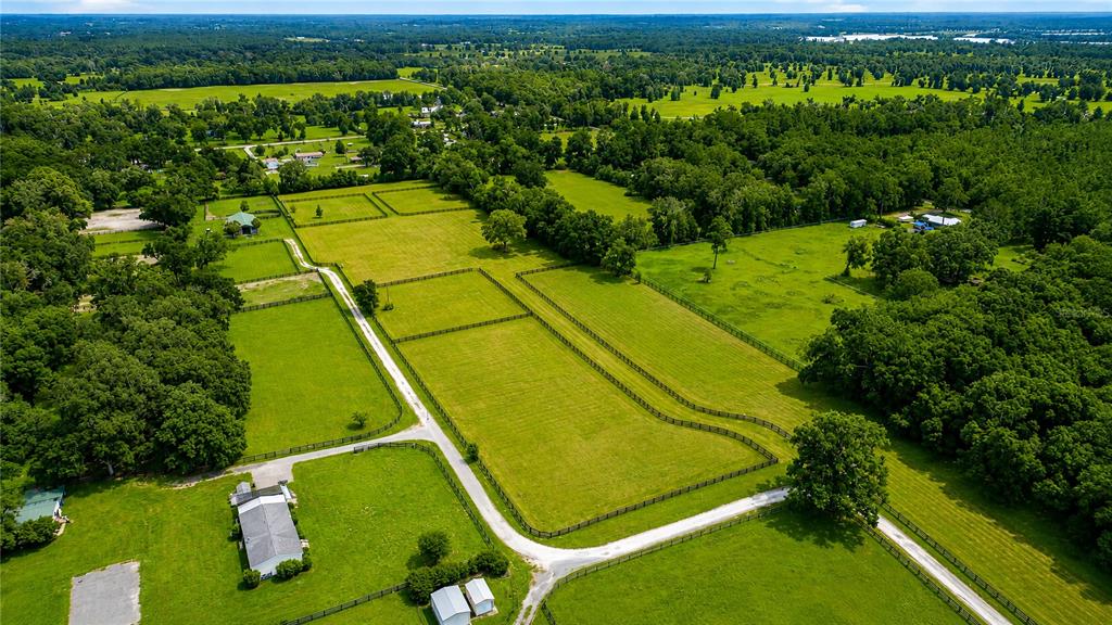 An aerial view shows a rural property with fenced pastures, a house, and outbuildings — TBD NW 100TH AVENUE, OCALA, FL