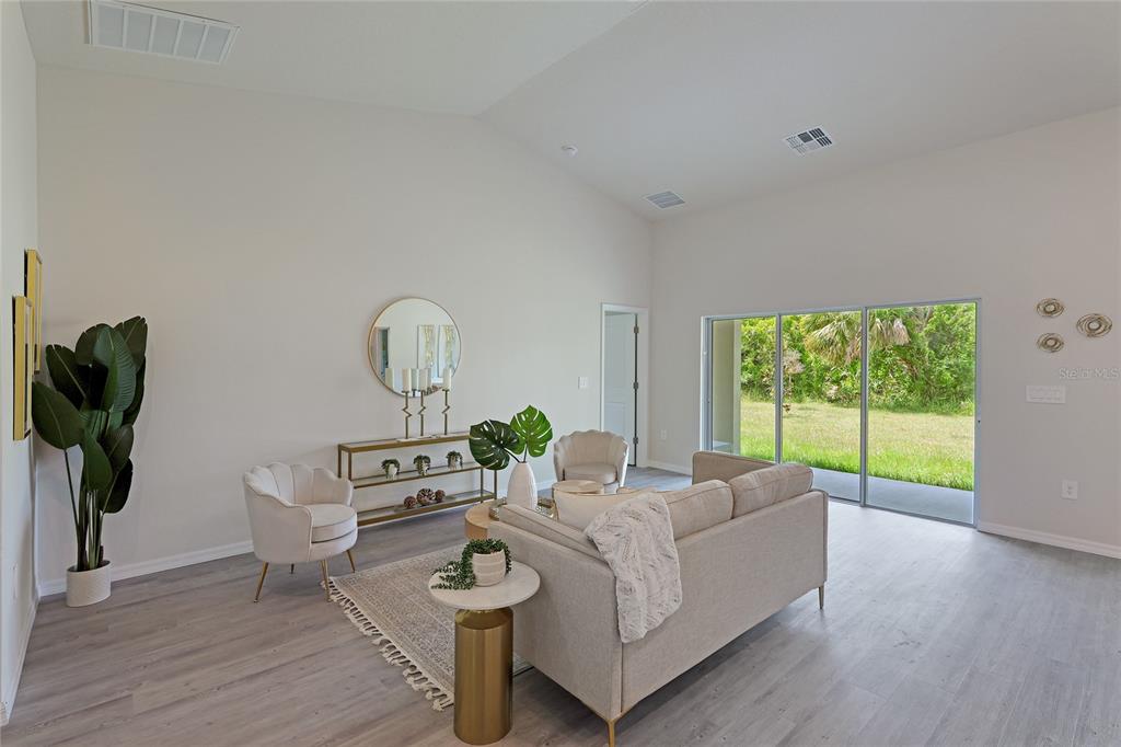 A living room features a sofa, two armchairs, a console table, and sliding glass doors — 3837 URIAH STREET, NORTH PORT, FL