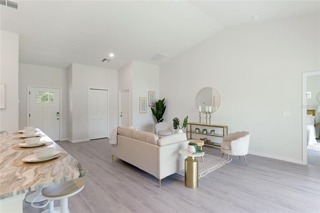 A living room with light wood flooring, a sofa, two armchairs, and a kitchen island — 3837 URIAH STREET, NORTH PORT, FL