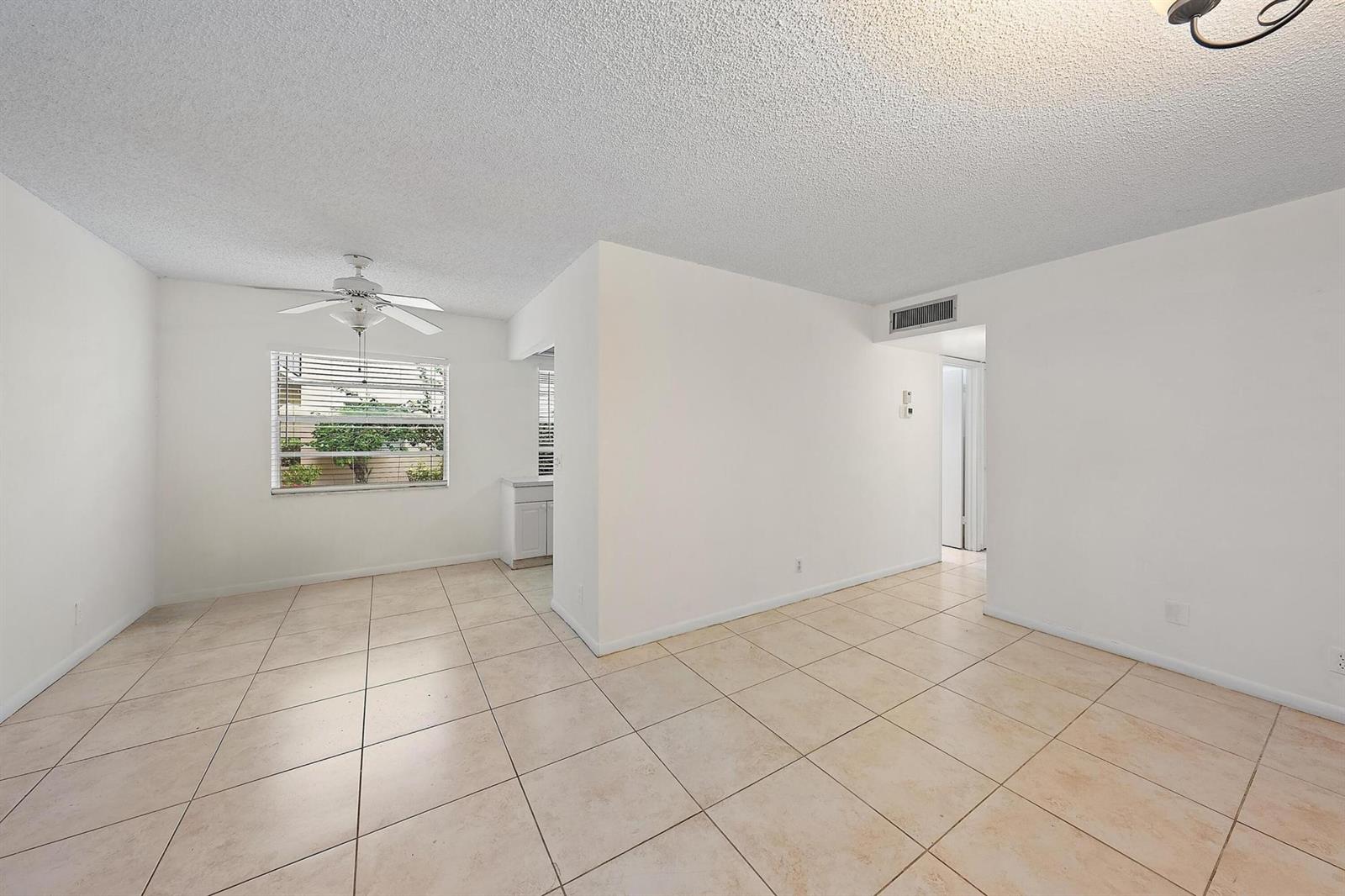 An empty room with white walls, beige tile flooring, a ceiling fan, and a window — 869 S Flanders S, Delray Beach FL 33484, DELRAY BEACH, FL