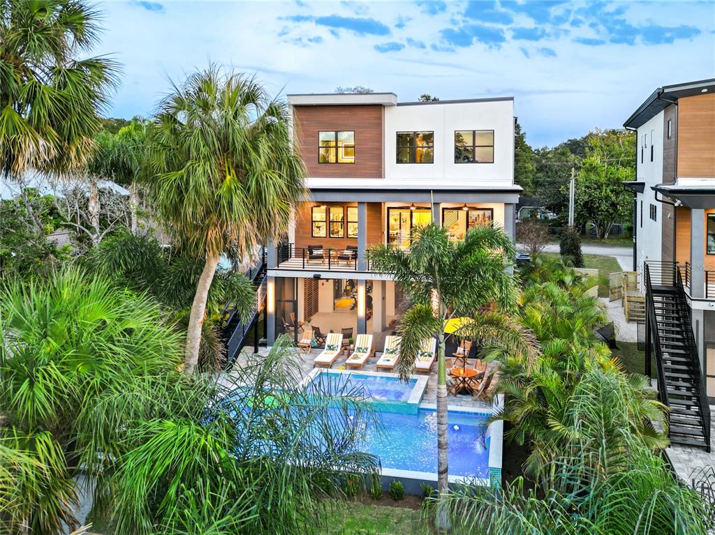 An exterior view of a three-story modern house featuring a swimming pool and palm trees — 2519 N RIVERSIDE DR, TAMPA, FL