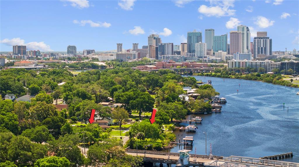 An aerial view shows a waterfront property with two red arrows pointing toward houses — 2519 N RIVERSIDE DR, TAMPA, FL