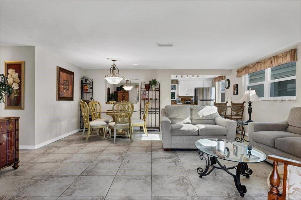 An open-concept living and dining area features tile flooring, neutral walls, and a kitchen view — 6154 MIDNIGHT PASS ROAD UNIT D11, SARASOTA, FL