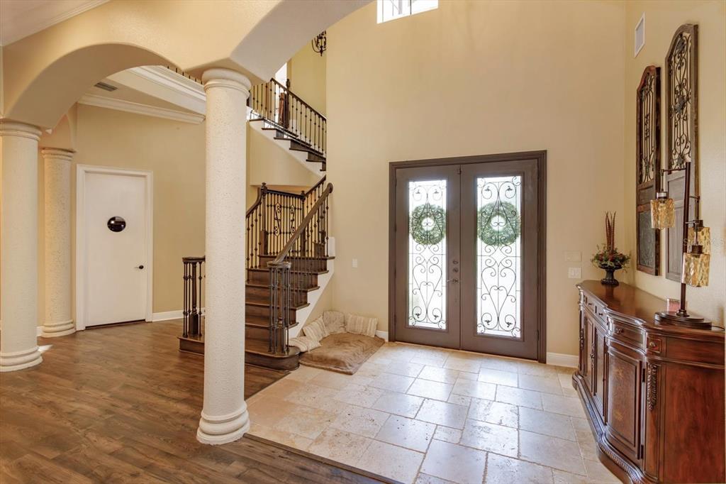 A foyer features a grand staircase, tile flooring, columns, and double glass-paneled entry doors — 5719 EMERSON POINTE WAY, ORLANDO, FL