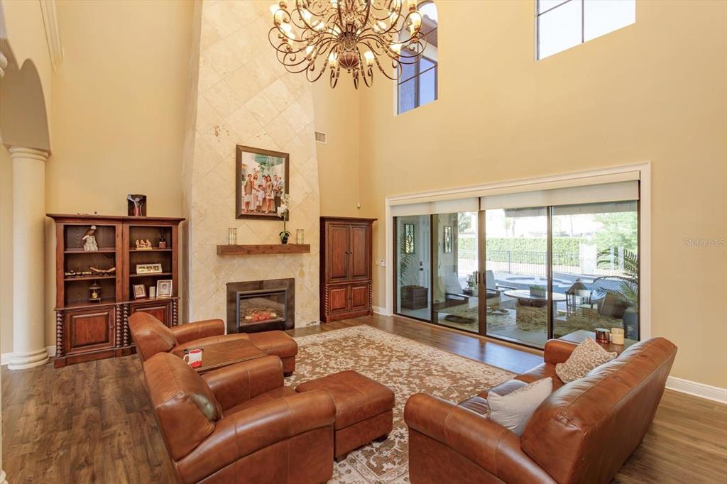 A living room features a stone fireplace, leather furniture, and sliding glass doors to a patio — 5719 EMERSON POINTE WAY, ORLANDO, FL