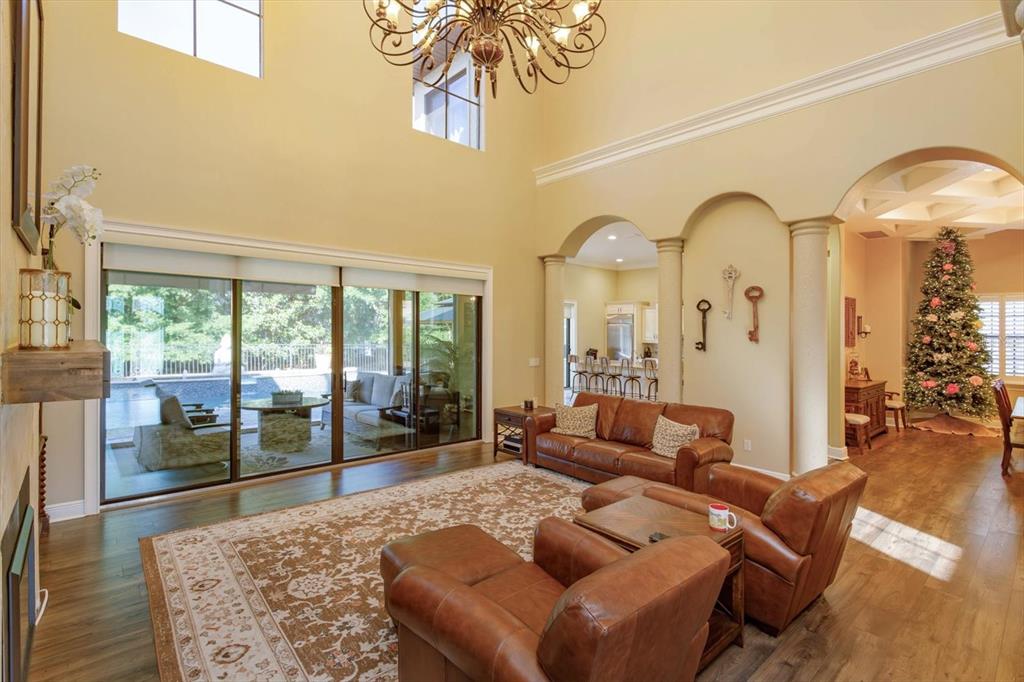 A spacious living room with high ceilings, leather furniture, a large rug, and sliding glass doors — 5719 EMERSON POINTE WAY, ORLANDO, FL