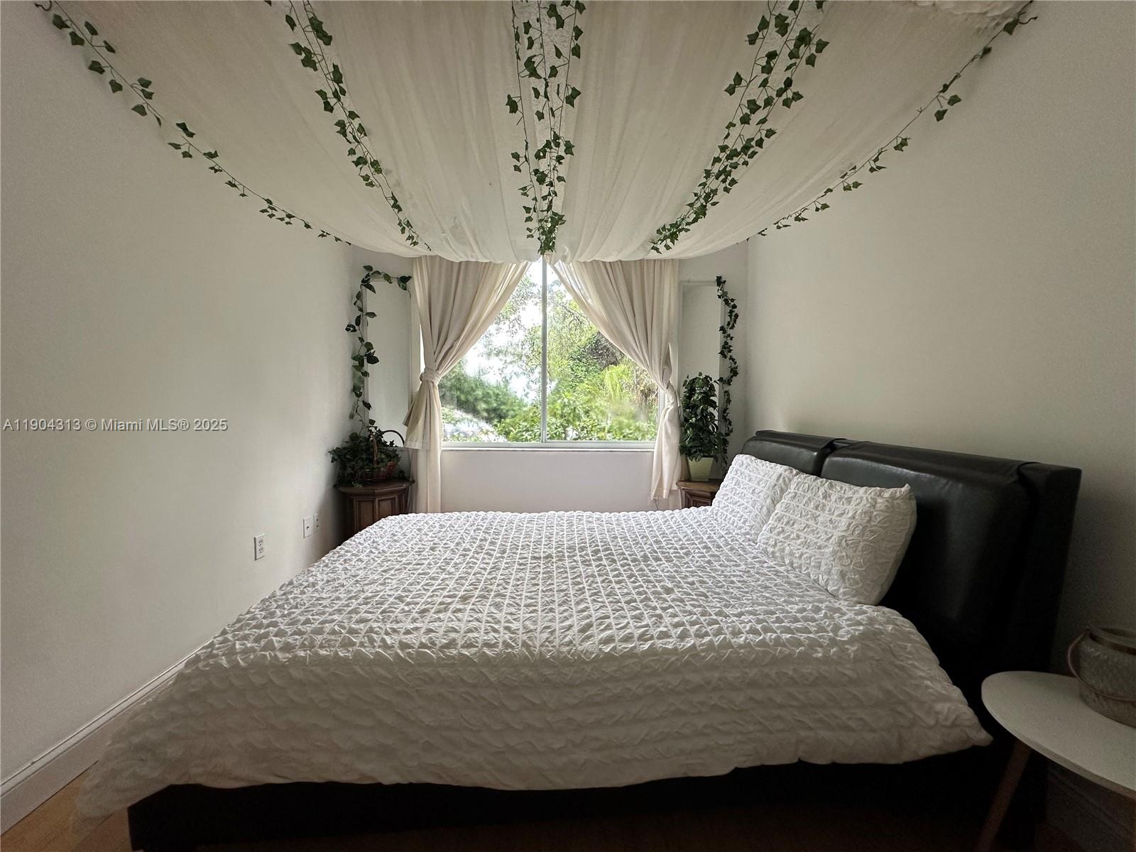 A bedroom features a bed with a textured white comforter and ceiling-draped fabric with vines — 1720 NW N River Dr # 305, Miami FL 33125, MIAMI, FL