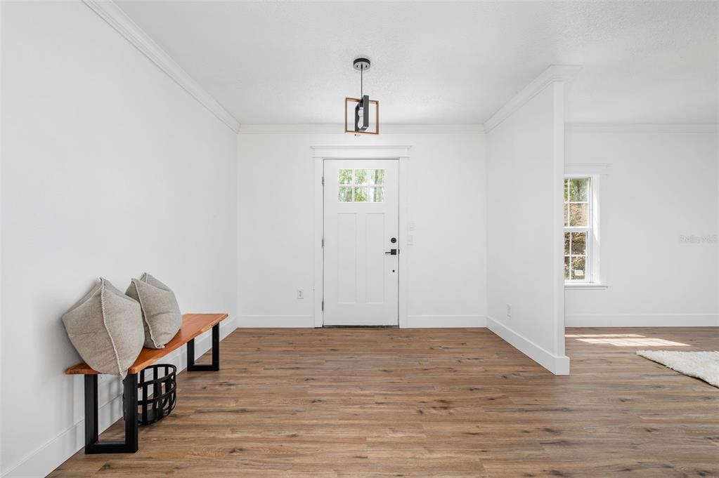 An entryway features wood-look flooring, white walls, a wooden bench, and a front door — 13076 SW 154TH STREET, ARCHER, FL