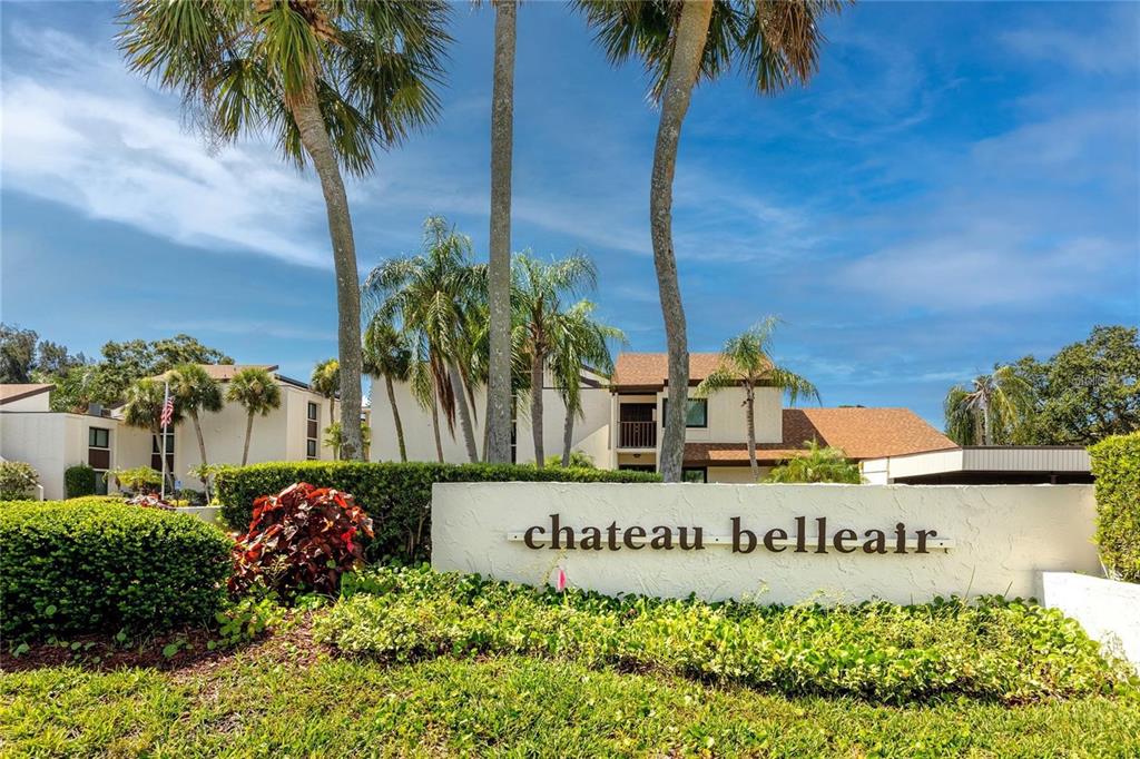 A white sign reading "chateau belleair" sits in front of multi-story apartment buildings and palm trees — 2209 BELLEAIR ROAD UNIT C3, CLEARWATER, FL