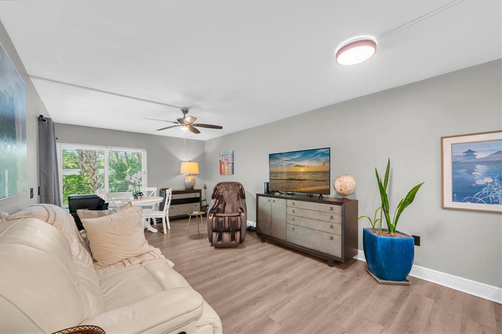 A living room features light wood flooring, a white sofa, a television console, and a recliner — 2209 BELLEAIR ROAD UNIT C3, CLEARWATER, FL