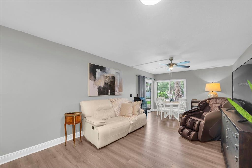 A living room features light gray walls, wood-look flooring, a cream sofa, and a massage chair — 2209 BELLEAIR ROAD UNIT C3, CLEARWATER, FL