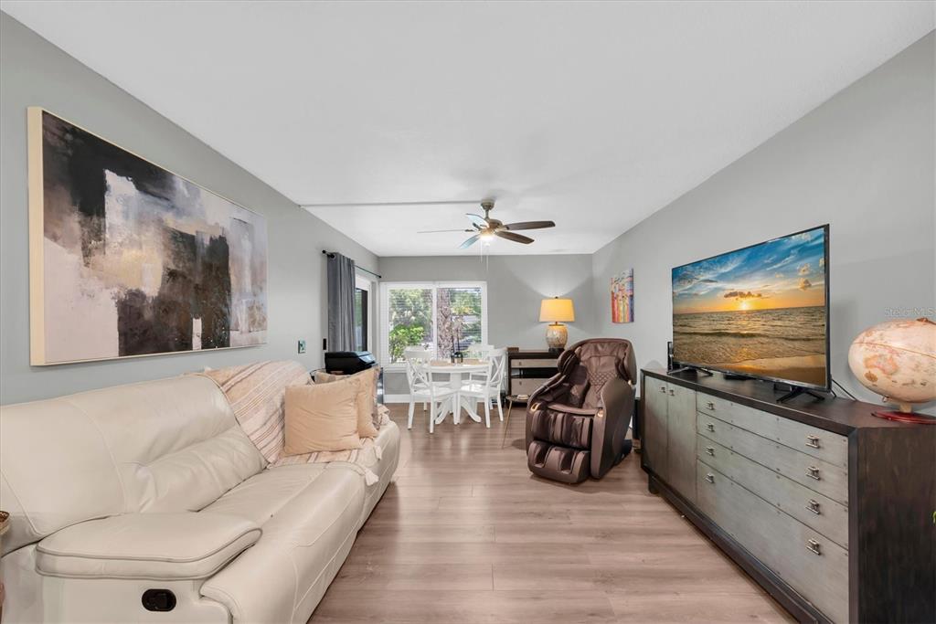 A living room features a white sofa, a television on a dresser, and a dining area — 2209 BELLEAIR ROAD UNIT C3, CLEARWATER, FL