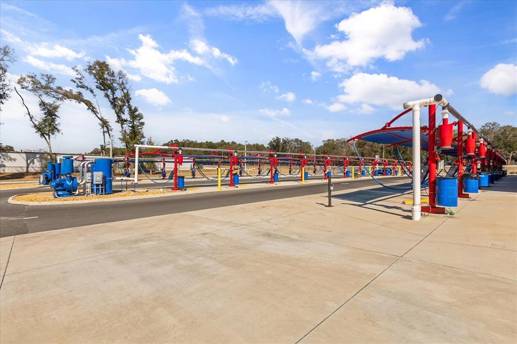 An outdoor car wash vacuum station with red support beams and blue trash cans — 9820 SE US HIGHWAY 441, BELLEVIEW, FL