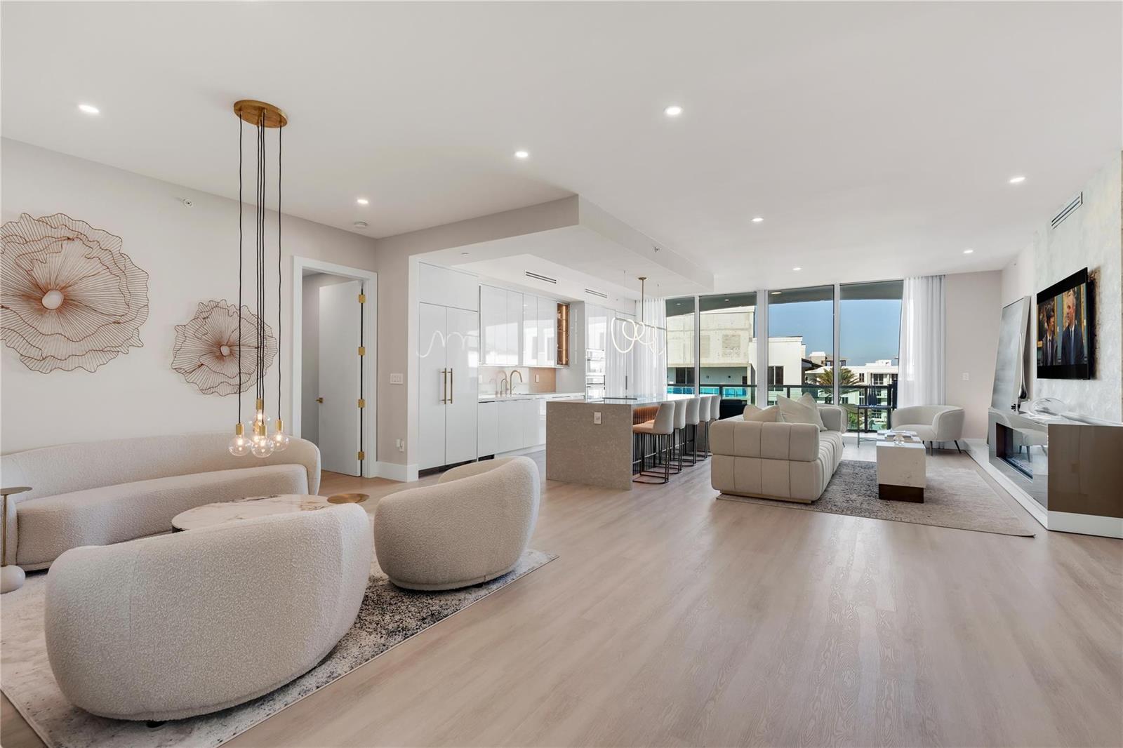 An open-concept living room and kitchen featuring light wood floors, neutral furniture, and floor-to-ceiling windows — 500 SE Mizner Boulevard # A902, Boca Raton FL 33432, BOCA RATON, FL