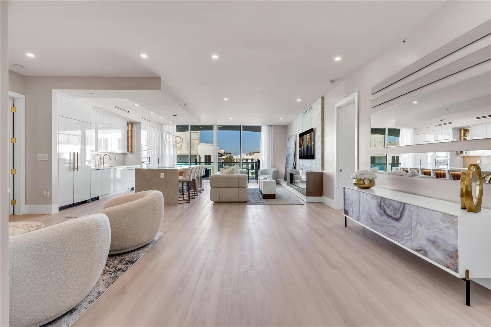 An open-concept living area features a modern kitchen, light wood flooring, and floor-to-ceiling windows — 500 SE Mizner Boulevard # A902, Boca Raton FL 33432, BOCA RATON, FL