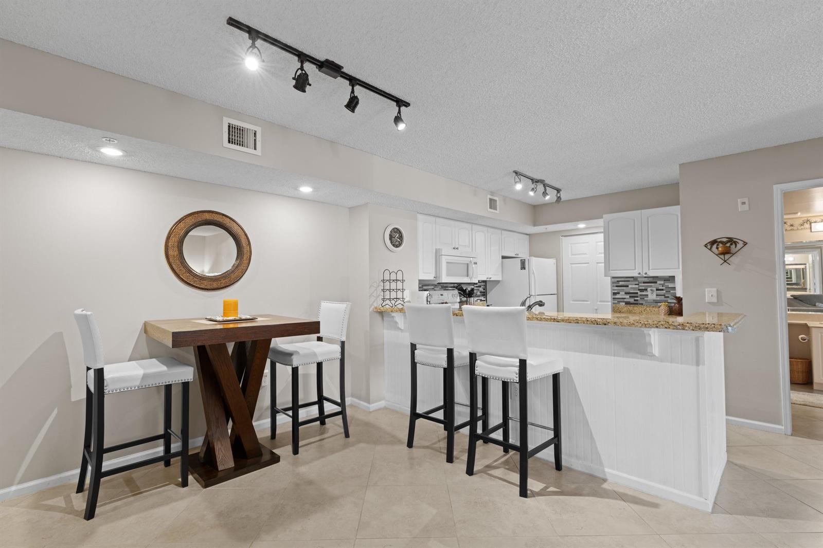 A kitchen with white cabinets, a granite breakfast bar, and a small dining table — 272 Village Boulevard # 7109, Tequesta FL 33469, TEQUESTA, FL