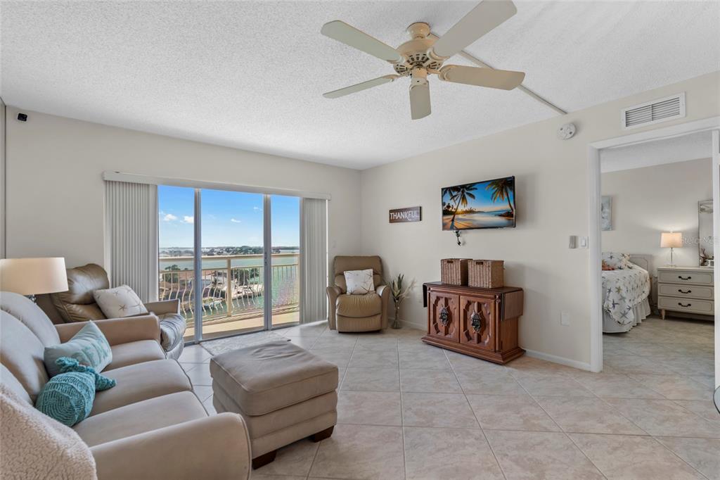 A living room features tile flooring, a ceiling fan, a television, and a balcony view — 4900 BRITTANY DRIVE S UNIT 808, ST PETERSBURG, FL