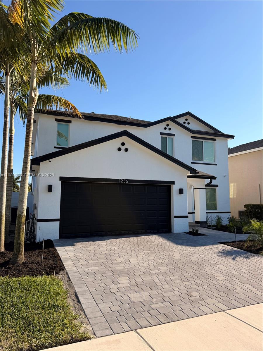 A two-story white house with a black garage door and a paved driveway — 1236 NW 208th St, Miami Gardens FL 33169, MIAMI GARDENS, FL