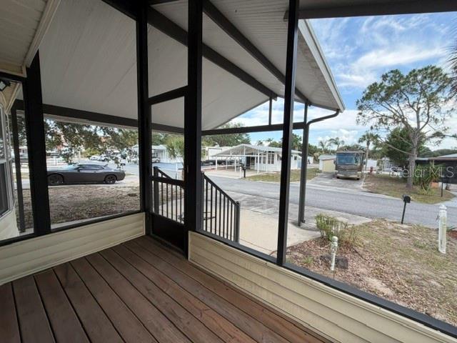 A screened-in porch with wooden decking overlooks a residential street with parked vehicles — 85 IRON LANE, HAINES CITY, FL
