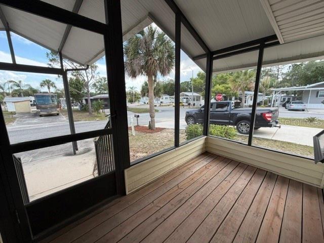 A screened-in porch with wood flooring overlooks a residential street with a parked truck — 85 IRON LANE, HAINES CITY, FL