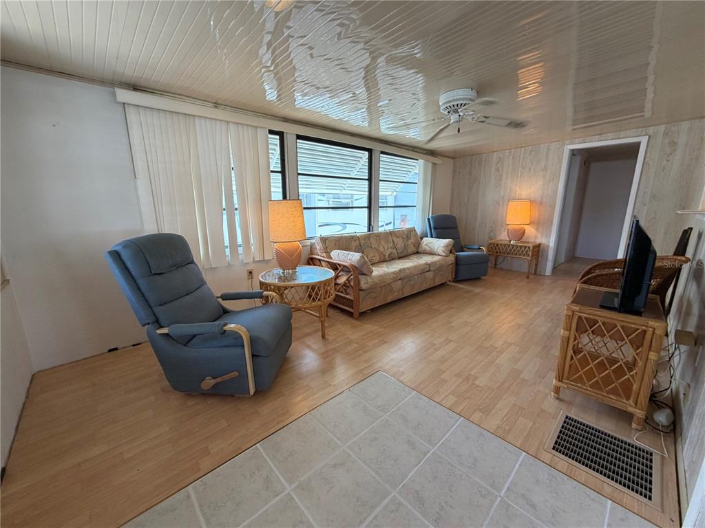 A living room features light wood-look flooring, a floral sofa, blue recliners, and paneled walls — 85 IRON LANE, HAINES CITY, FL