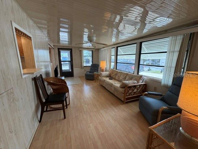 A living room features wood-paneled walls, light wood flooring, a ceiling fan, and large windows — 85 IRON LANE, HAINES CITY, FL