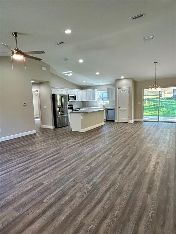 An open-concept kitchen and living area features gray wood-look flooring and white cabinetry — 15637 SE 84TH TERRACE, SUMMERFIELD, FL