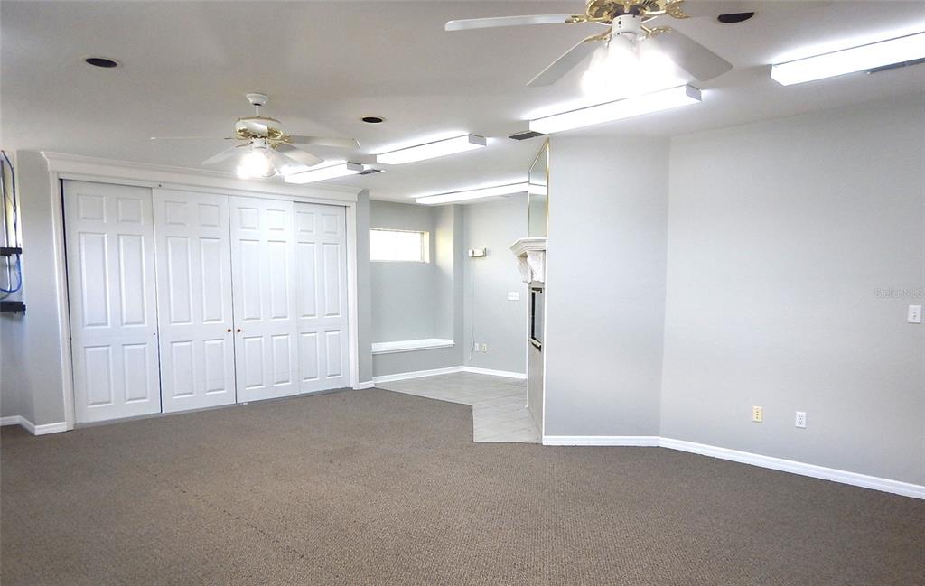 A carpeted room features white bi-fold closet doors, a fireplace, and multiple ceiling light fixtures — 3921 NW 97TH BOULEVARD UNIT 202, GAINESVILLE, FL